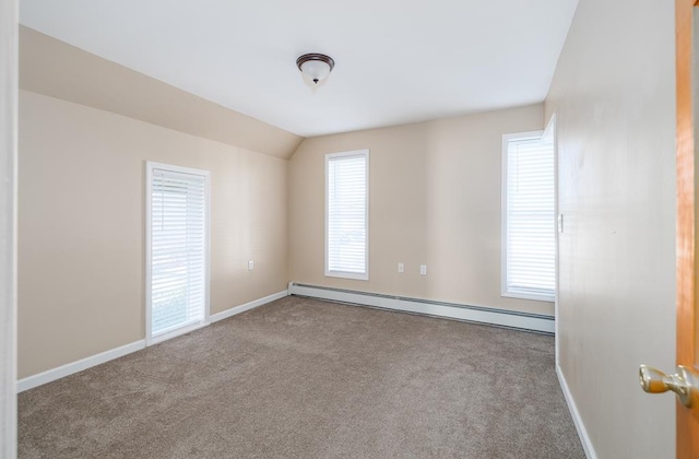 spare room featuring lofted ceiling, light carpet, and a baseboard heating unit