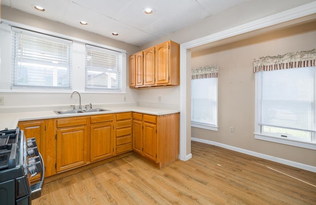 kitchen featuring a wealth of natural light, sink, stainless steel range oven, and light hardwood / wood-style flooring