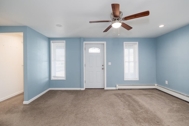 foyer entrance with carpet flooring, ceiling fan, a healthy amount of sunlight, and baseboard heating