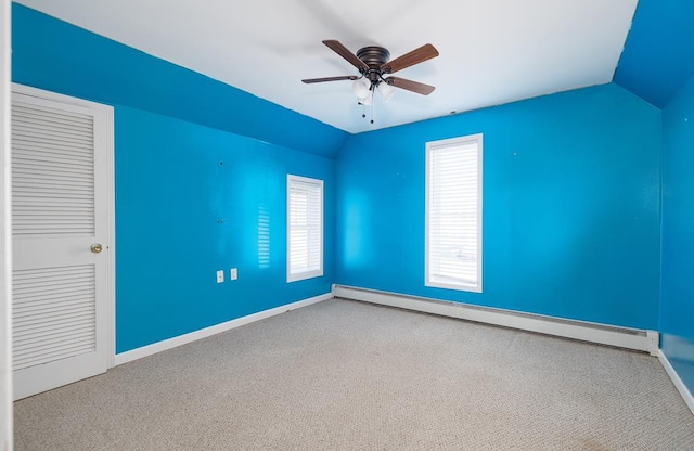 empty room featuring ceiling fan, carpet floors, vaulted ceiling, and a baseboard heating unit