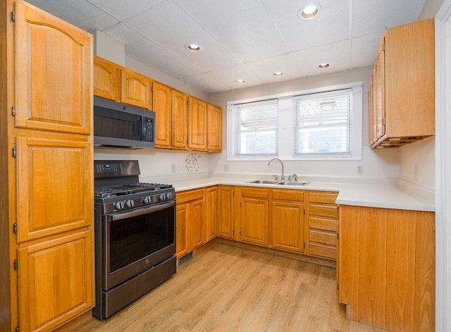 kitchen featuring a drop ceiling, sink, light wood-type flooring, and appliances with stainless steel finishes