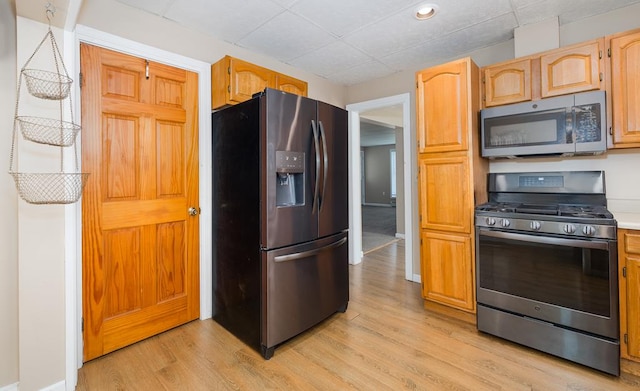 kitchen featuring light brown cabinetry, appliances with stainless steel finishes, and light hardwood / wood-style flooring