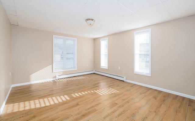 spare room with light hardwood / wood-style floors, a wealth of natural light, and a baseboard heating unit