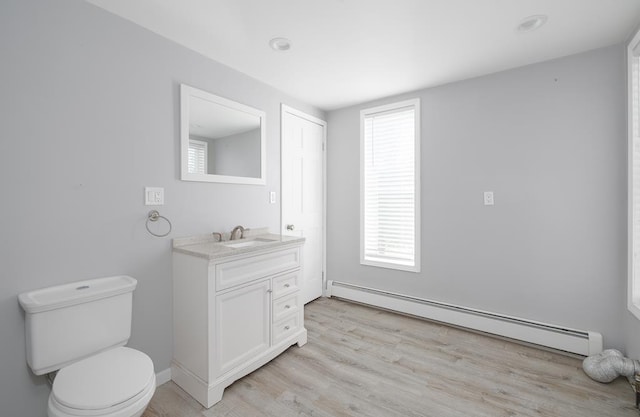 bathroom with hardwood / wood-style flooring, vanity, toilet, and baseboard heating