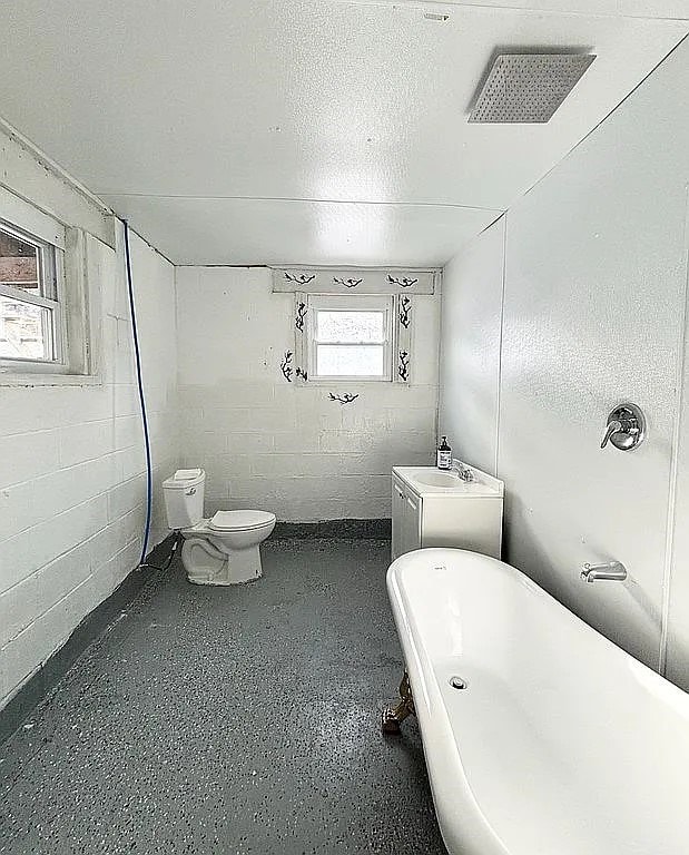 bathroom with a textured ceiling, toilet, and a tub