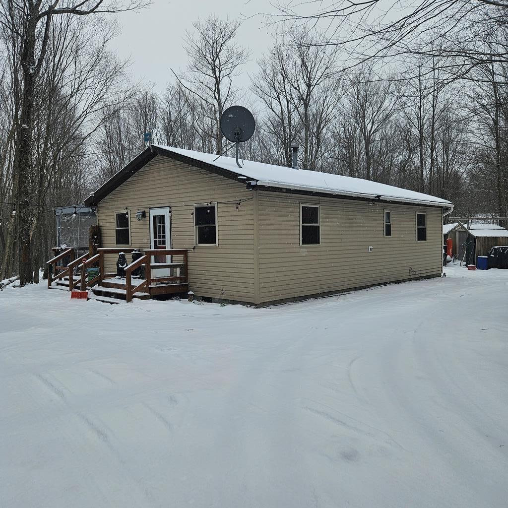 snow covered back of property with a deck