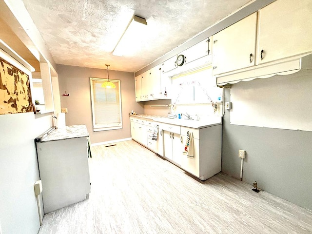 kitchen featuring decorative light fixtures, white cabinetry, and light hardwood / wood-style flooring