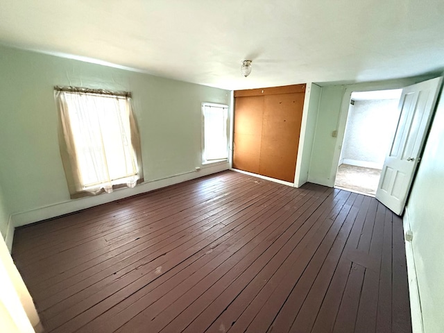 unfurnished bedroom with a closet, wood-type flooring, and multiple windows