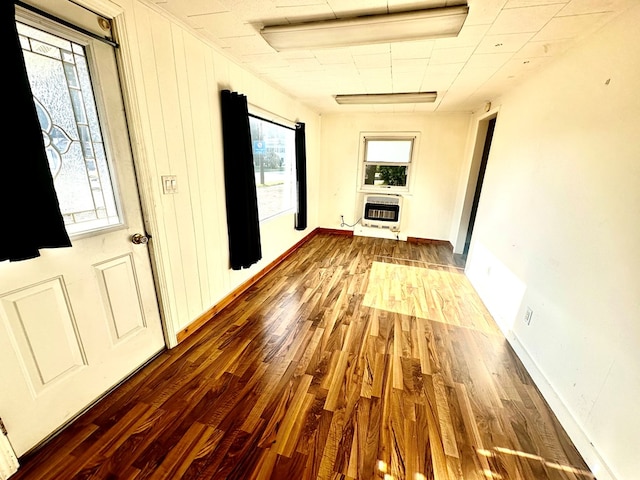 hall featuring heating unit, a wealth of natural light, and wood-type flooring