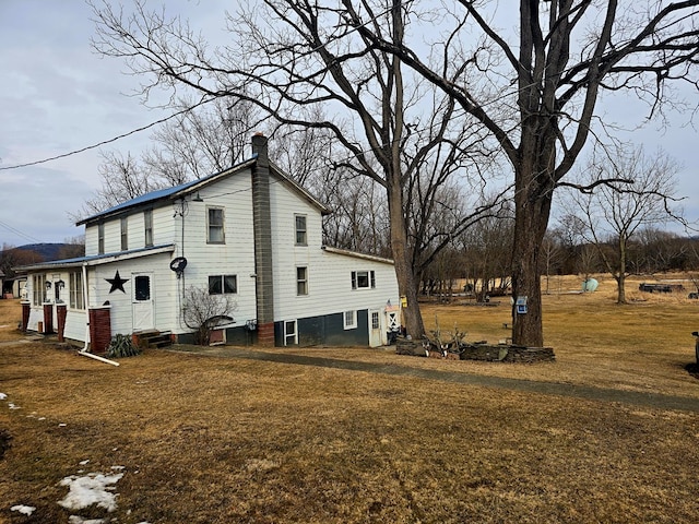 view of side of property with a lawn and a chimney