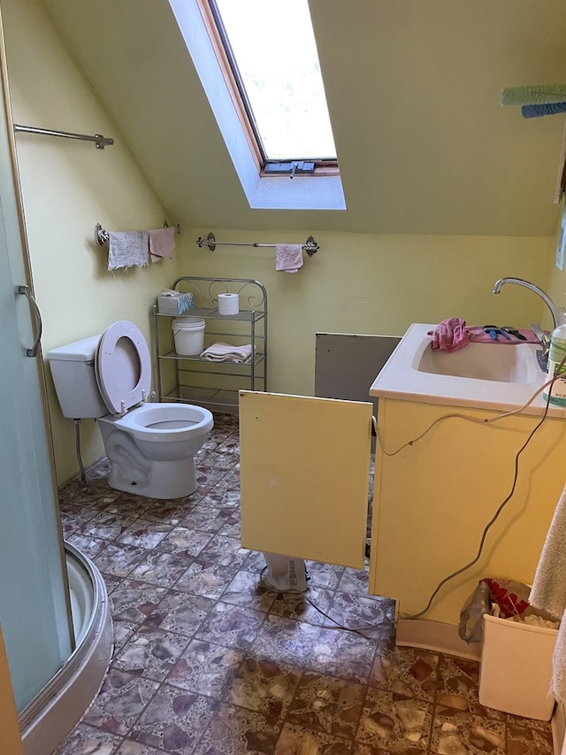 bathroom with vaulted ceiling with skylight, vanity, and toilet