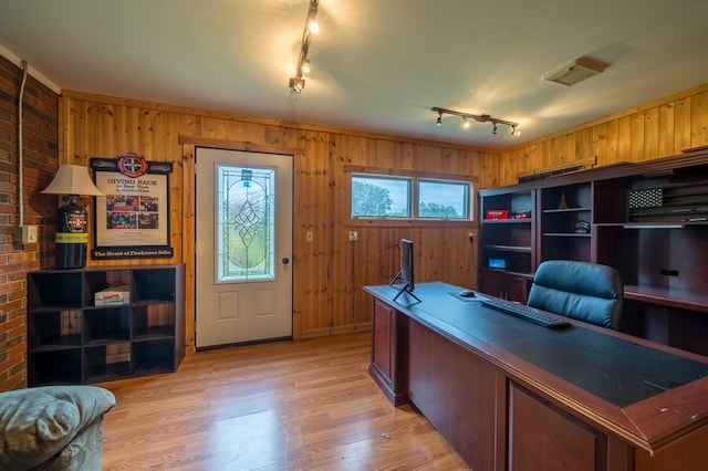 home office featuring light wood-type flooring, track lighting, and wood walls