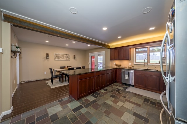 kitchen featuring sink, french doors, stainless steel appliances, kitchen peninsula, and dark stone countertops