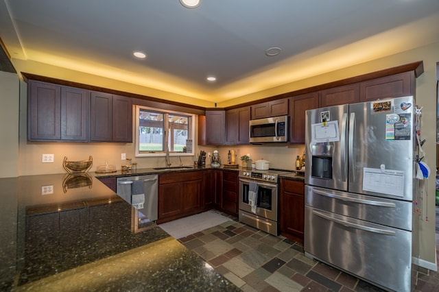 kitchen with dark stone countertops, sink, and appliances with stainless steel finishes