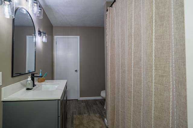 bathroom featuring hardwood / wood-style floors, vanity, a textured ceiling, and toilet