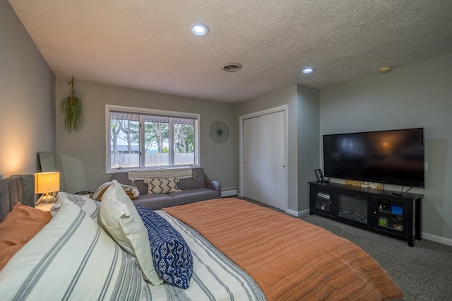 bedroom featuring carpet, a textured ceiling, and a baseboard heating unit