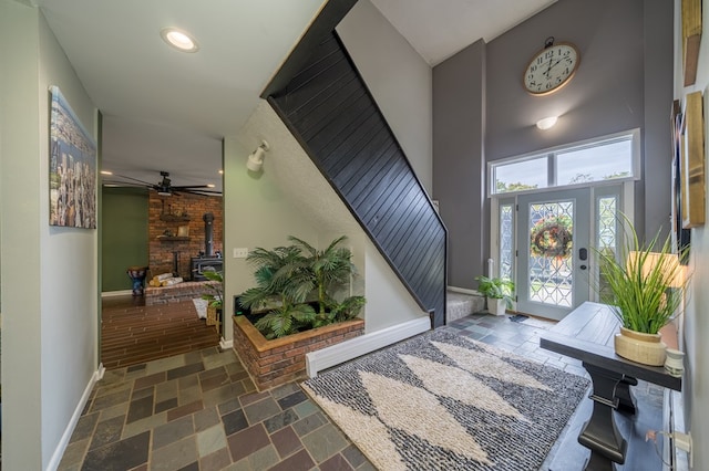 foyer entrance featuring a wood stove and ceiling fan