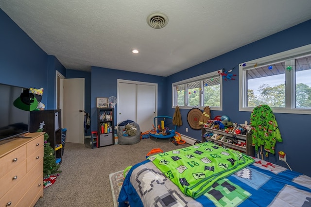 bedroom with light colored carpet, a textured ceiling, and a closet