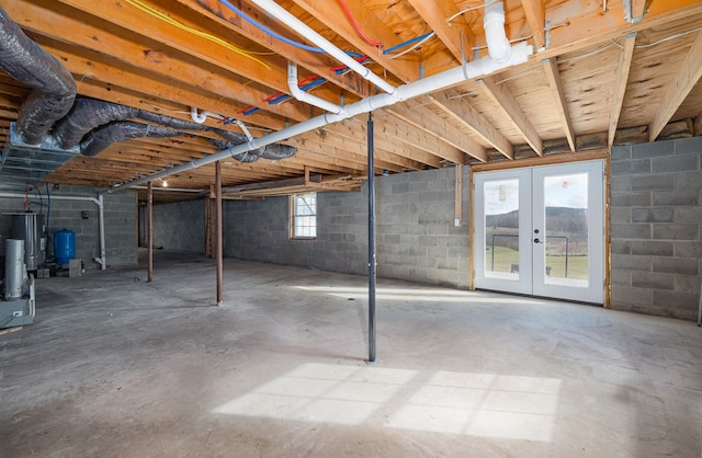 basement featuring a healthy amount of sunlight, water heater, and french doors