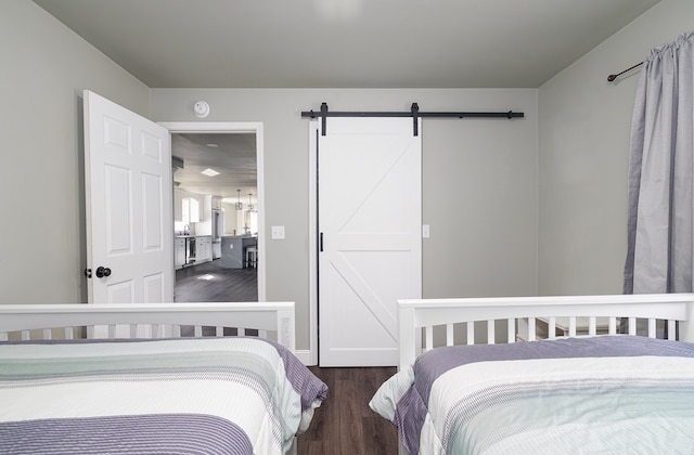 bedroom with a barn door and dark wood-type flooring