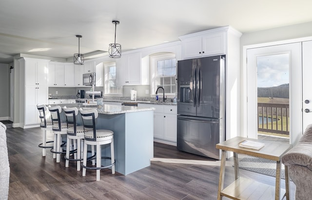 kitchen with dark wood-type flooring, white cabinets, hanging light fixtures, a kitchen island, and black fridge with ice dispenser