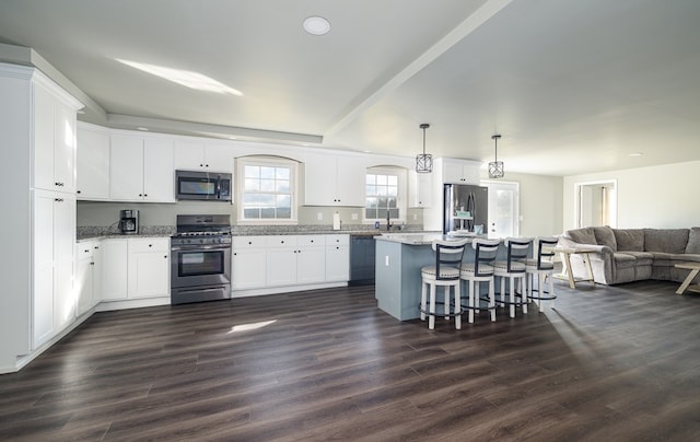 kitchen featuring light stone counters, hanging light fixtures, a kitchen island, and stainless steel appliances