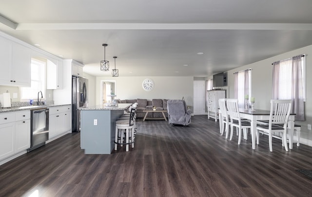 kitchen featuring a center island, dark wood-type flooring, stainless steel appliances, light stone counters, and white cabinets