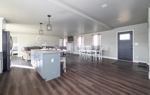 kitchen with stainless steel fridge, a center island, dark hardwood / wood-style floors, and pendant lighting