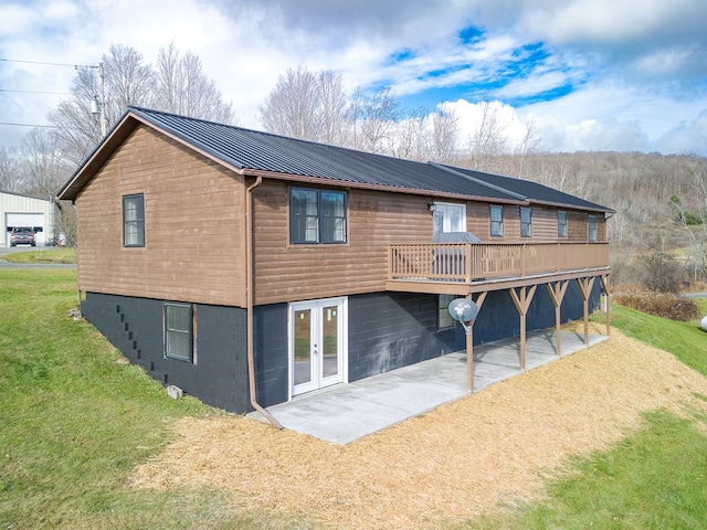 rear view of house featuring a lawn, a wooden deck, a patio area, and french doors