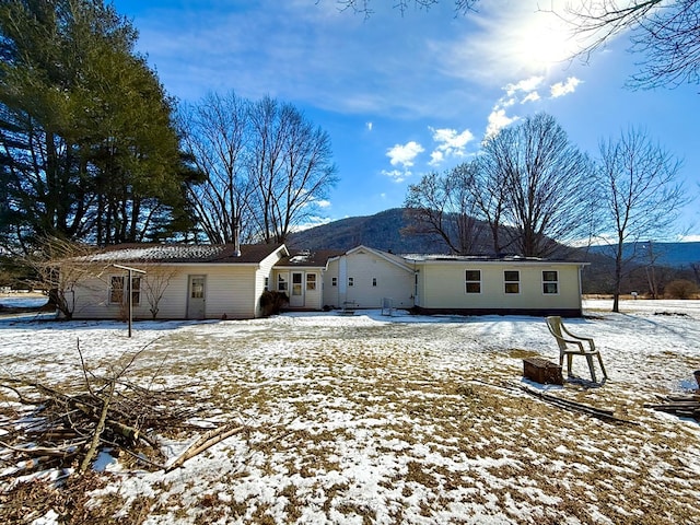 snow covered back of property with a mountain view