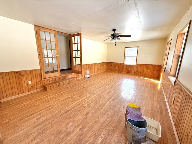 interior space with hardwood / wood-style flooring, french doors, and wood walls