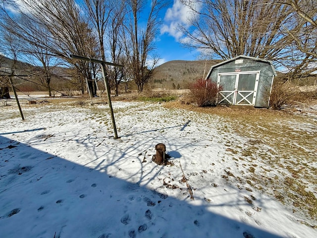 snowy yard with a mountain view and a shed