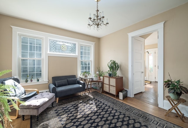 sitting room with baseboard heating, wood-type flooring, and a notable chandelier