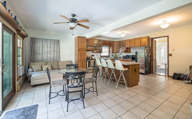 dining space with ceiling fan, beam ceiling, and light tile patterned floors