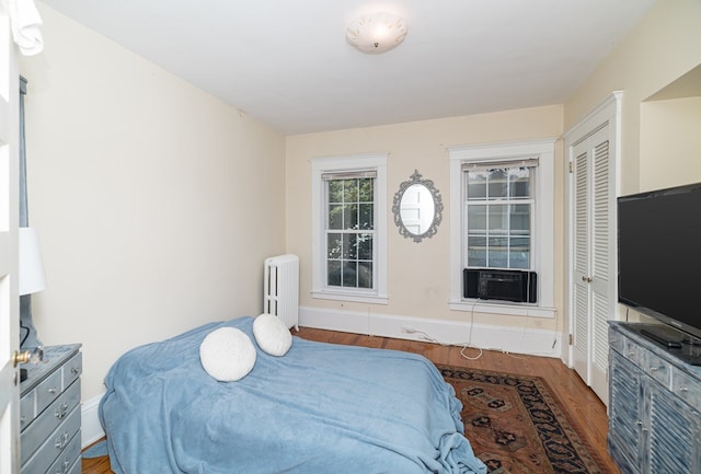 bedroom with cooling unit, dark hardwood / wood-style flooring, and radiator