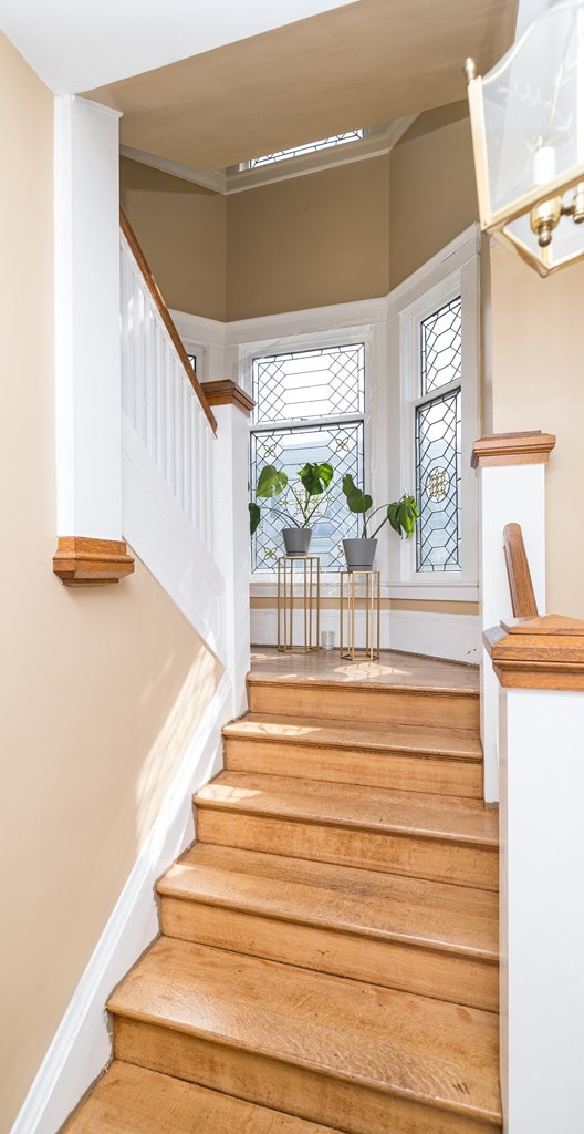 staircase featuring ornamental molding and a notable chandelier