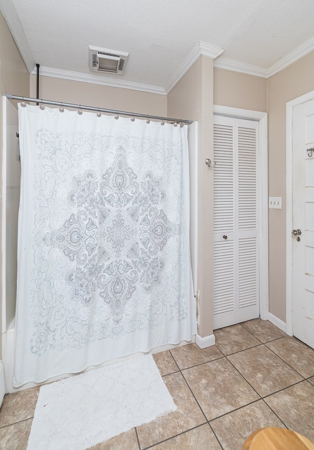 bathroom with a textured ceiling, tile patterned floors, and ornamental molding