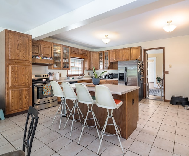 kitchen with a breakfast bar, light tile patterned floors, stainless steel appliances, and a kitchen island