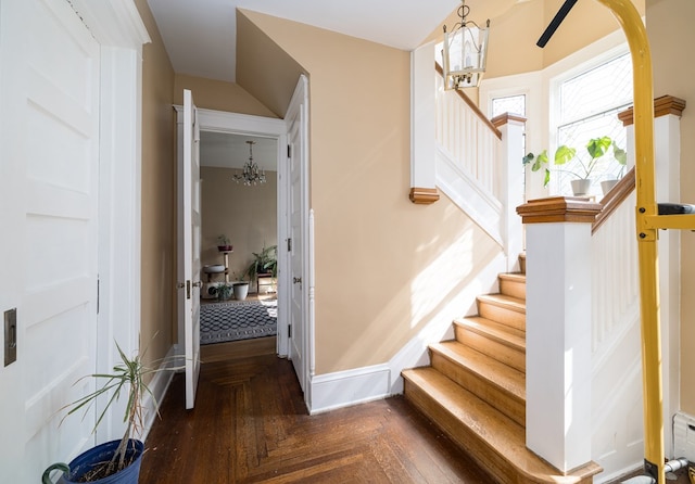 staircase with parquet floors and a chandelier