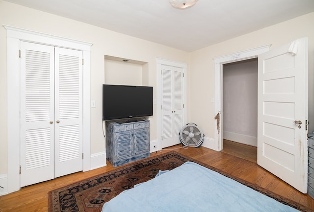 bedroom featuring wood-type flooring and two closets