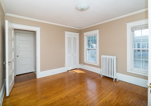 unfurnished room featuring hardwood / wood-style floors, plenty of natural light, crown molding, and radiator