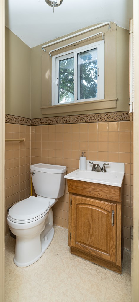 bathroom with vanity, tile walls, and toilet