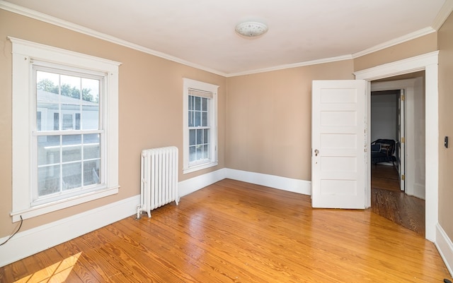 spare room featuring light hardwood / wood-style floors, radiator, and ornamental molding