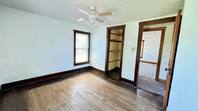spare room with baseboards, wood-type flooring, a textured ceiling, and a ceiling fan
