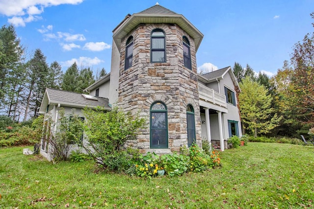 back of property with a lawn and a balcony