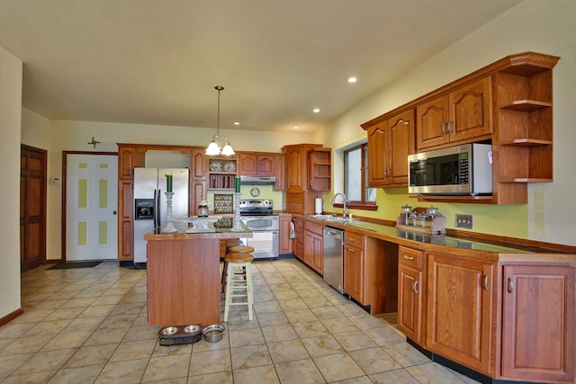 kitchen with appliances with stainless steel finishes, a kitchen breakfast bar, sink, pendant lighting, and a kitchen island