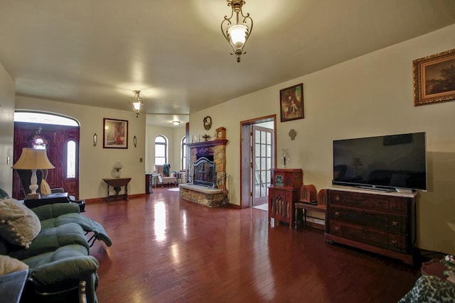 living room featuring a stone fireplace and wood-type flooring