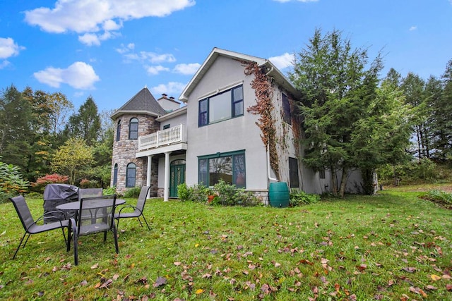 back of house featuring a lawn and a balcony