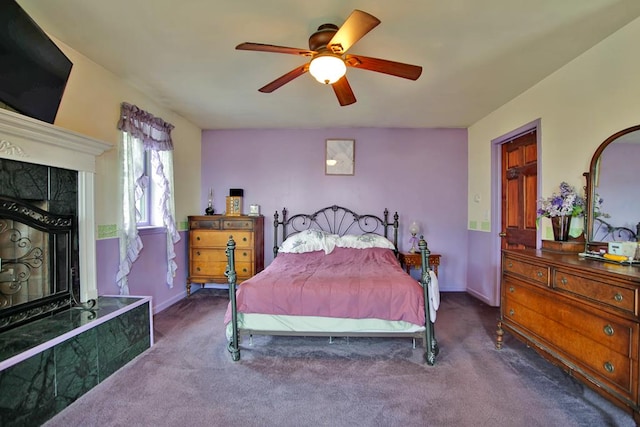 carpeted bedroom featuring a high end fireplace and ceiling fan