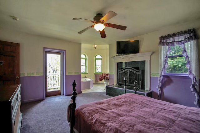 carpeted bedroom featuring ceiling fan and a tiled fireplace